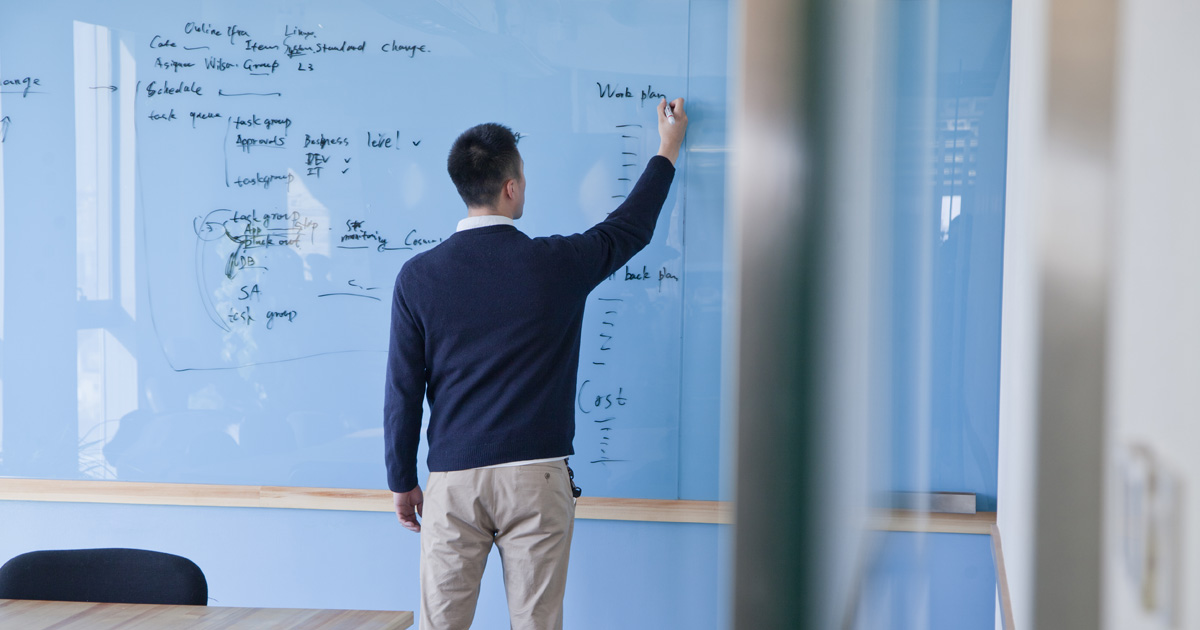 Businessman writing notes on the glass board