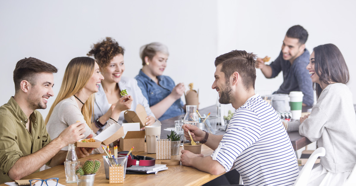 Multicultural team of coworkers eating a healthy lunch together at the office