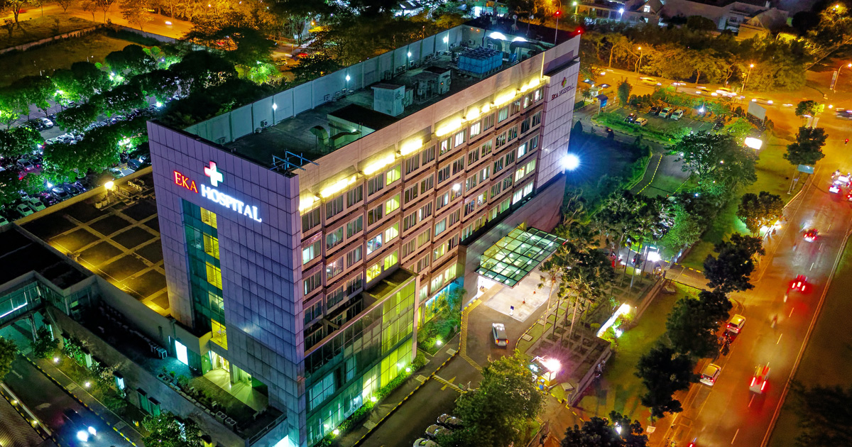 Hospital beside vehicle park and road at night