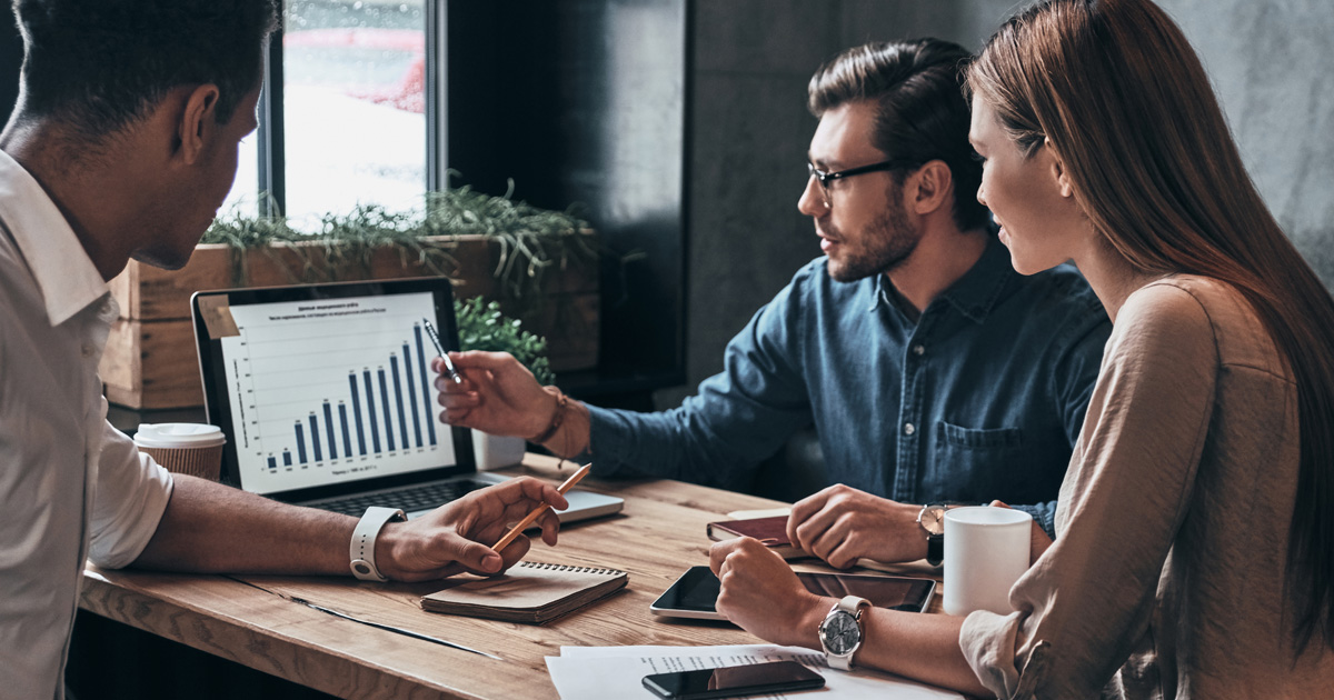 Group of young confident business people analyzing data using computer while spending time in the office