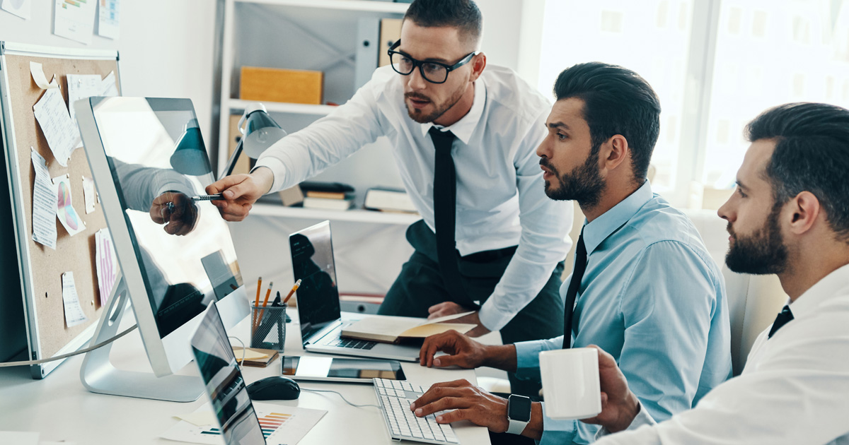 Group of young modern men in formalwear working using computers while sitting in the office