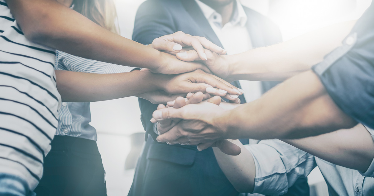 Close up view of young business people putting their hands together
