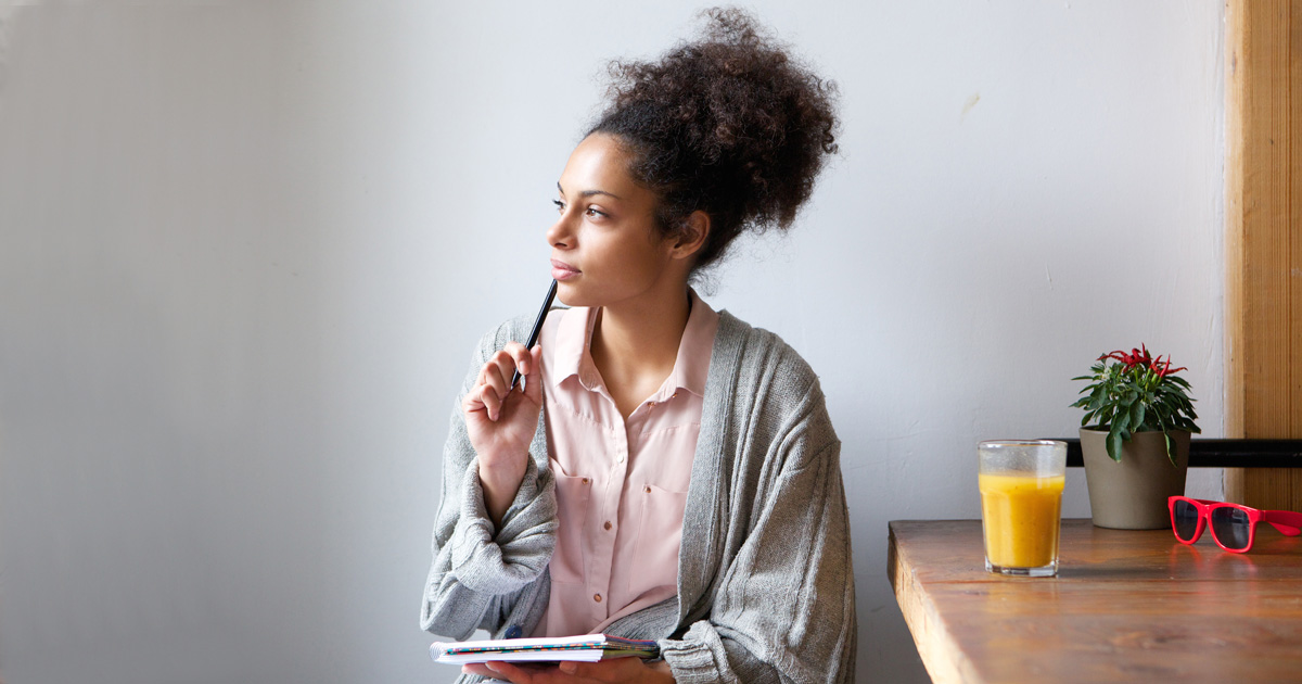 Portrait of a young woman sitting at home with pen and paper
