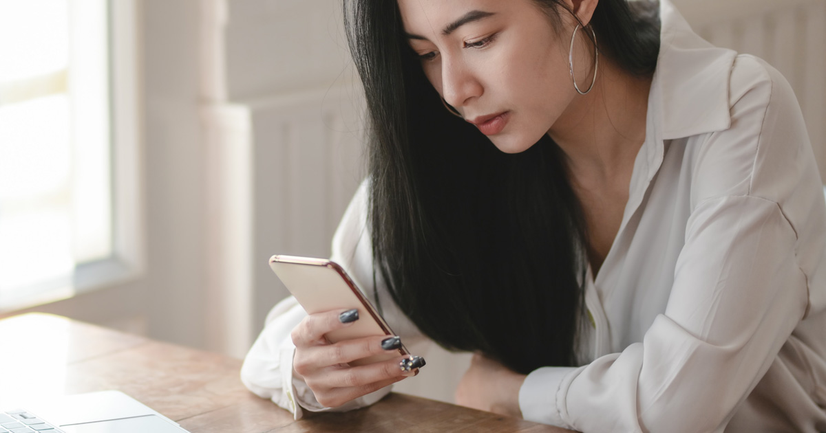 Woman in white long sleeve shirt using smartphone