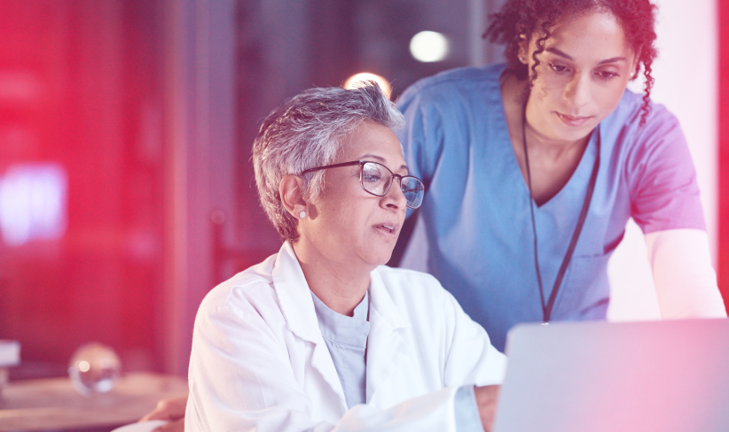 Two healthcare workers sitting at computer talking