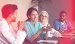 Healthcare professionals sitting at a conference table discussing possibilities of design thinking in healthcare delivery