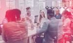 Group of young professionals sitting at a conference table during a meeting.