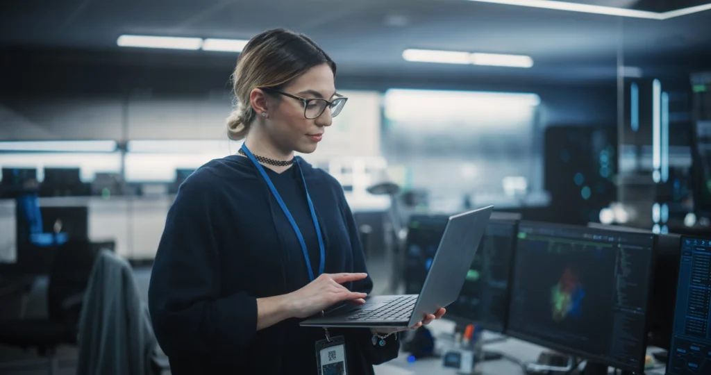 Female tech specialist looking at laptop while configuring data governance strategy.