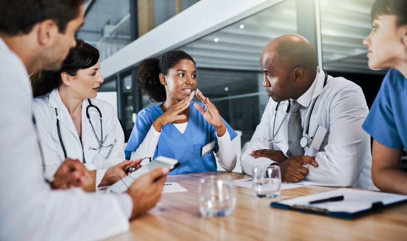 Group of doctors and nurses sitting at a table and discussing updates to their change management strategy.