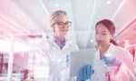Two women working in pharmaceuticals looking at a tablet