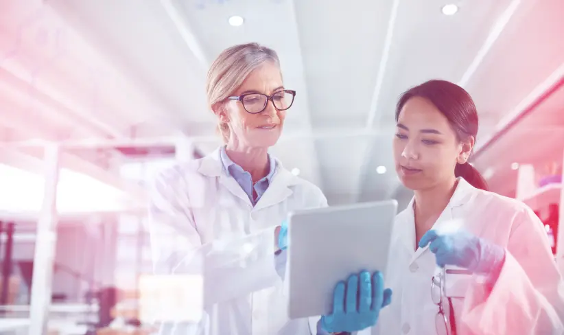 Two women working in pharmaceuticals looking at a tablet