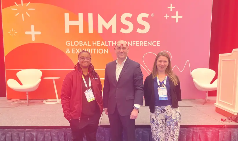 Three consultants from SEI standing in front of HIMSS 2026 banner