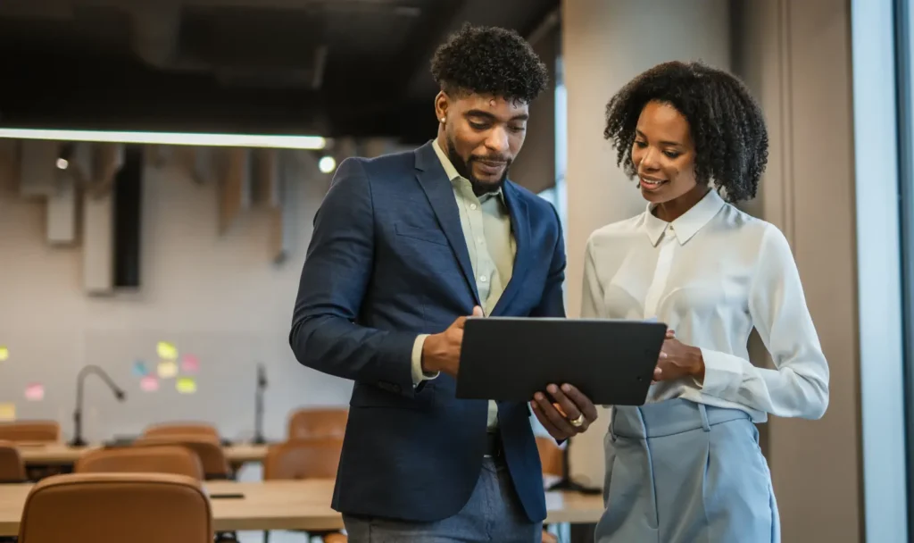 Two corporate professionals looking at a tablet and discussing their cloud migration strategy