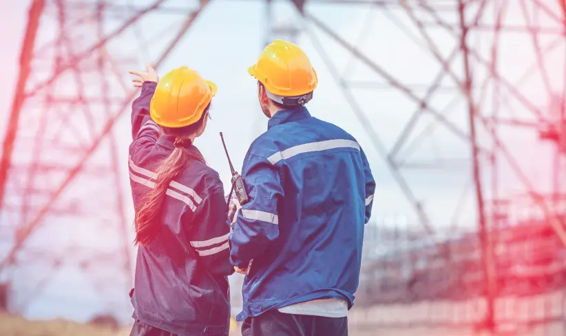 Two energy & utilities workers on the field looking at equipment