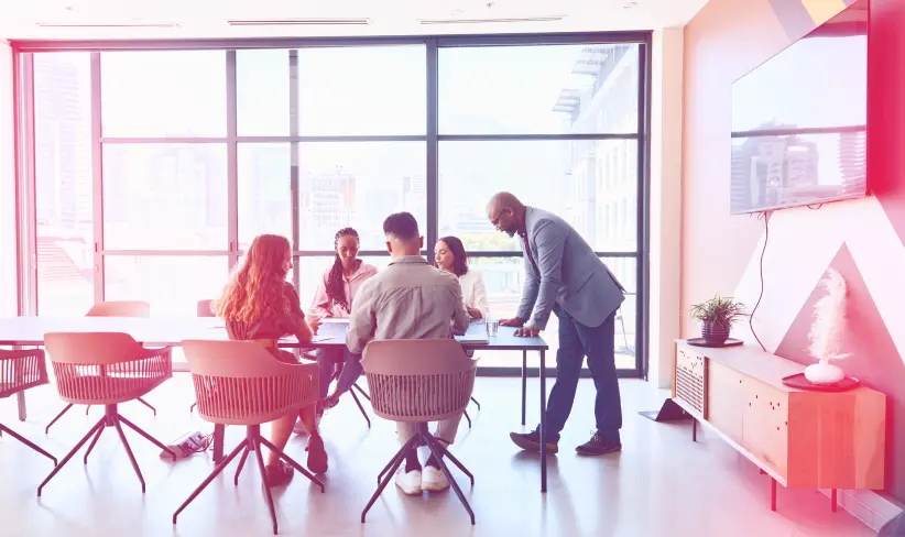 Group of people working in an office sitting an a table building with AI